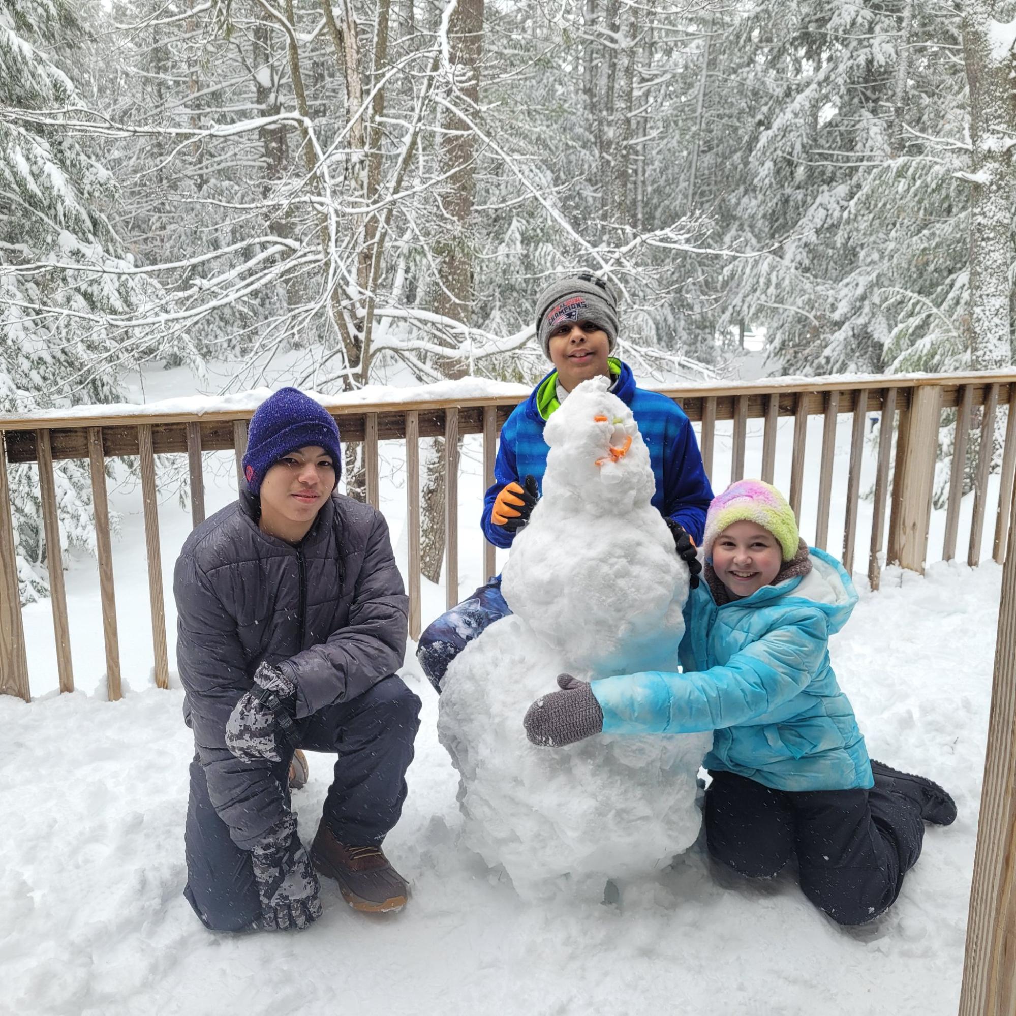 Three summer camp kids building a snowman during a winter week at Camp Starfish