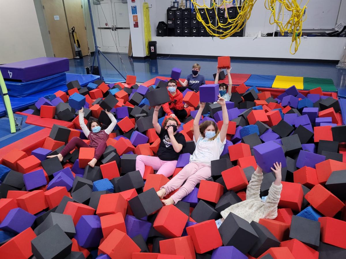 Group of camper teens playing in a gym of foam squares
