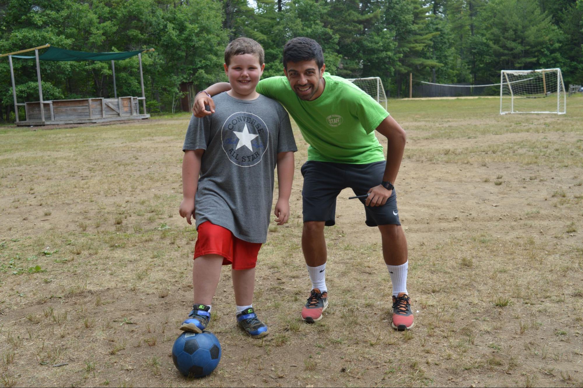 Camper and Counselor playing soccer and smiling at camera at Camp Starfish