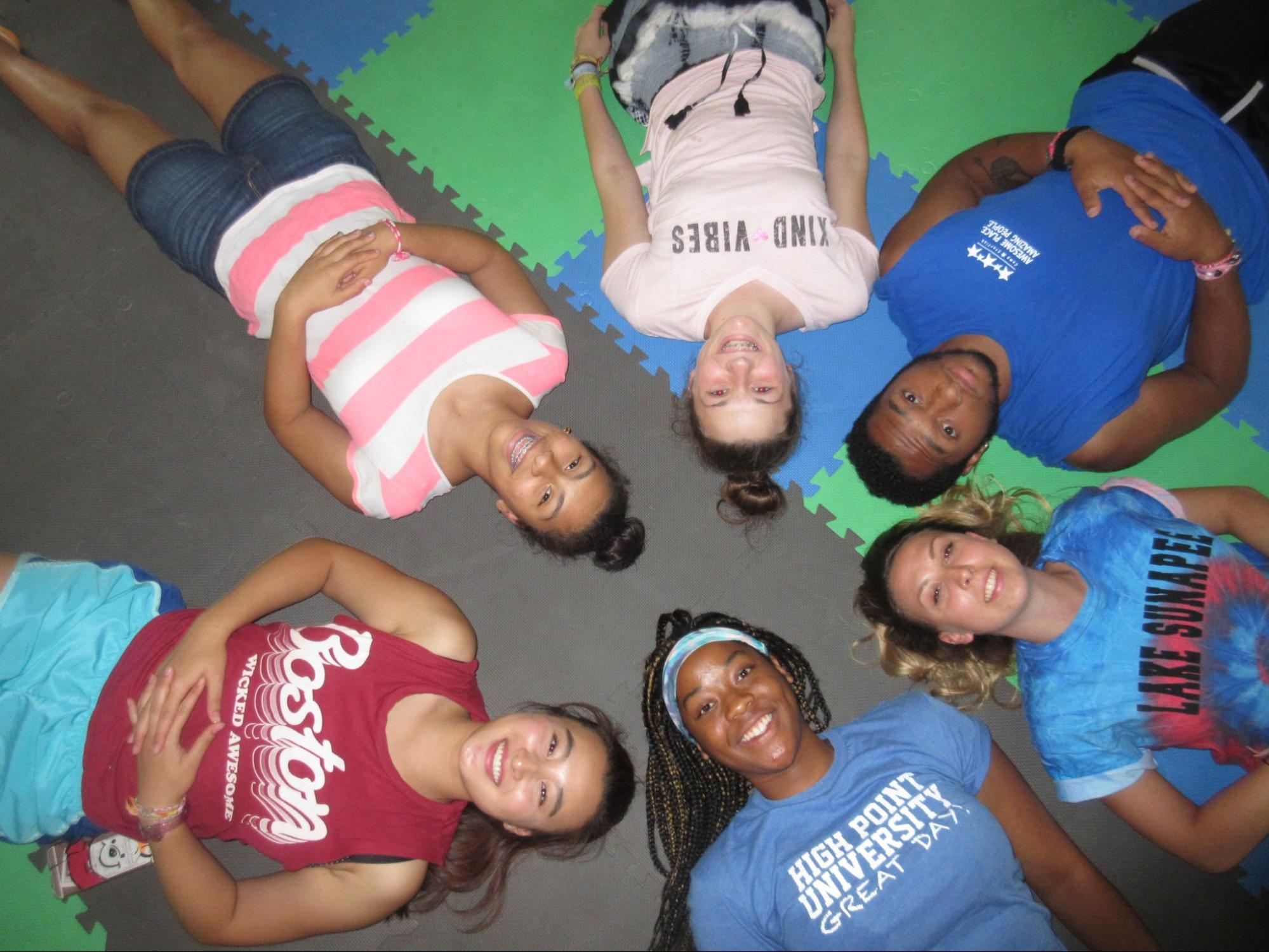 6 summer camp kids laying on the floor in a star configuration