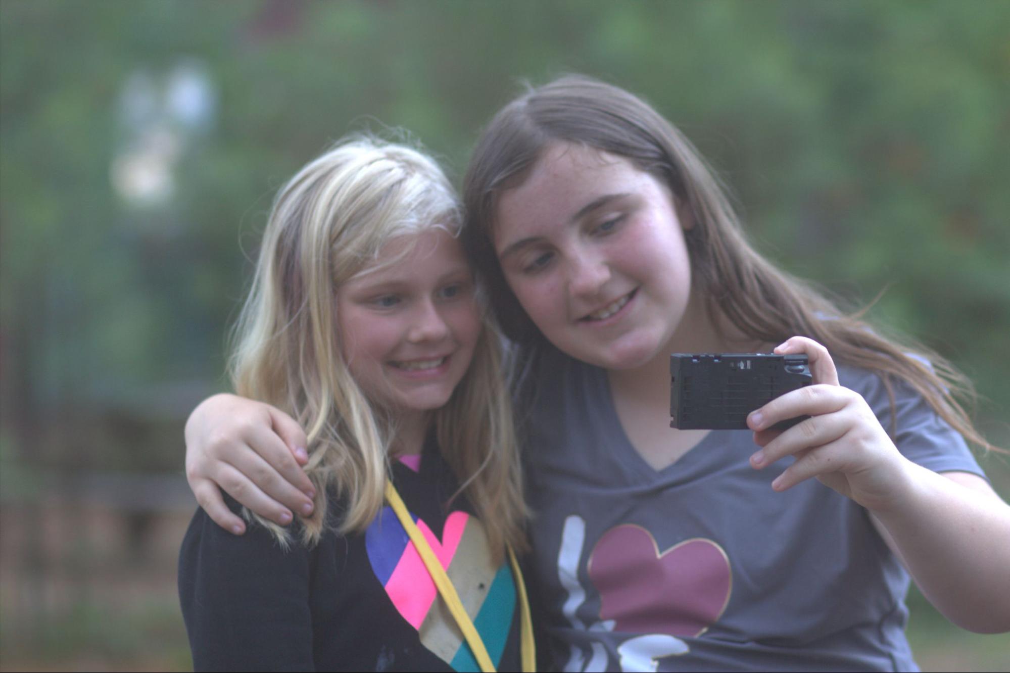 Two teen camp girls taking a selfie on a disposable camera