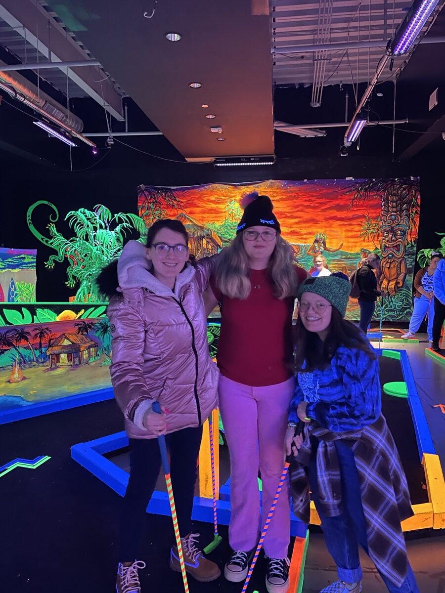 Three teens at Teen Adventure Week playing mini golf